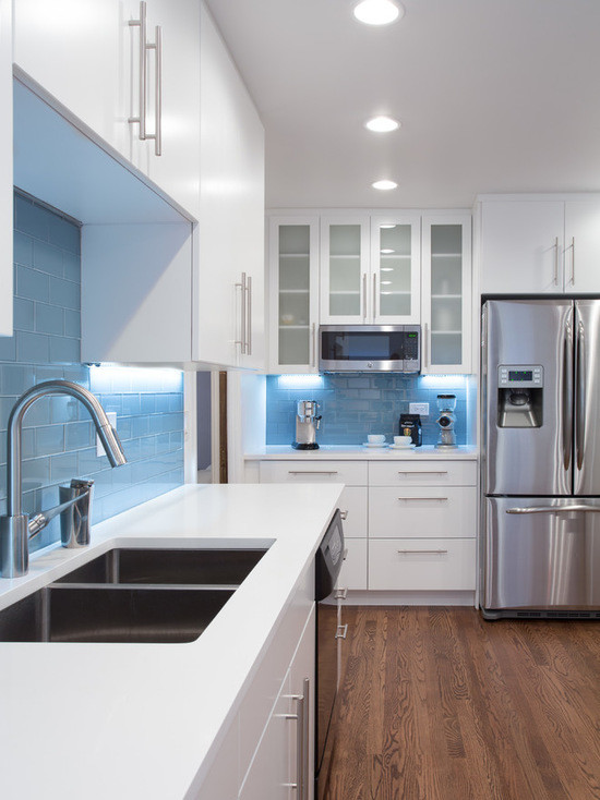 This is an example of a medium sized modern galley kitchen/diner in Chicago with a submerged sink, flat-panel cabinets, white cabinets, copper worktops, blue splashback, metro tiled splashback, stainless steel appliances, medium hardwood flooring and no island.