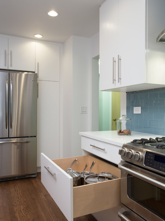 Foto på ett mellanstort funkis kök, med en undermonterad diskho, släta luckor, vita skåp, bänkskiva i akrylsten, blått stänkskydd, stänkskydd i tunnelbanekakel, rostfria vitvaror och mellanmörkt trägolv