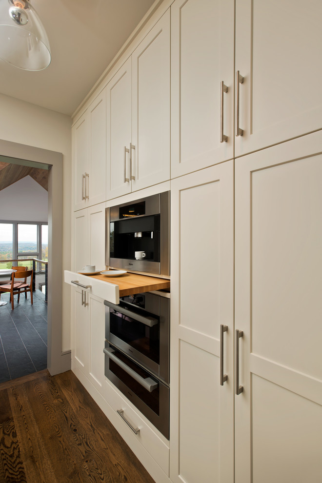 This is an example of a contemporary kitchen in Boston with marble worktops, stainless steel appliances, dark hardwood flooring and an island.