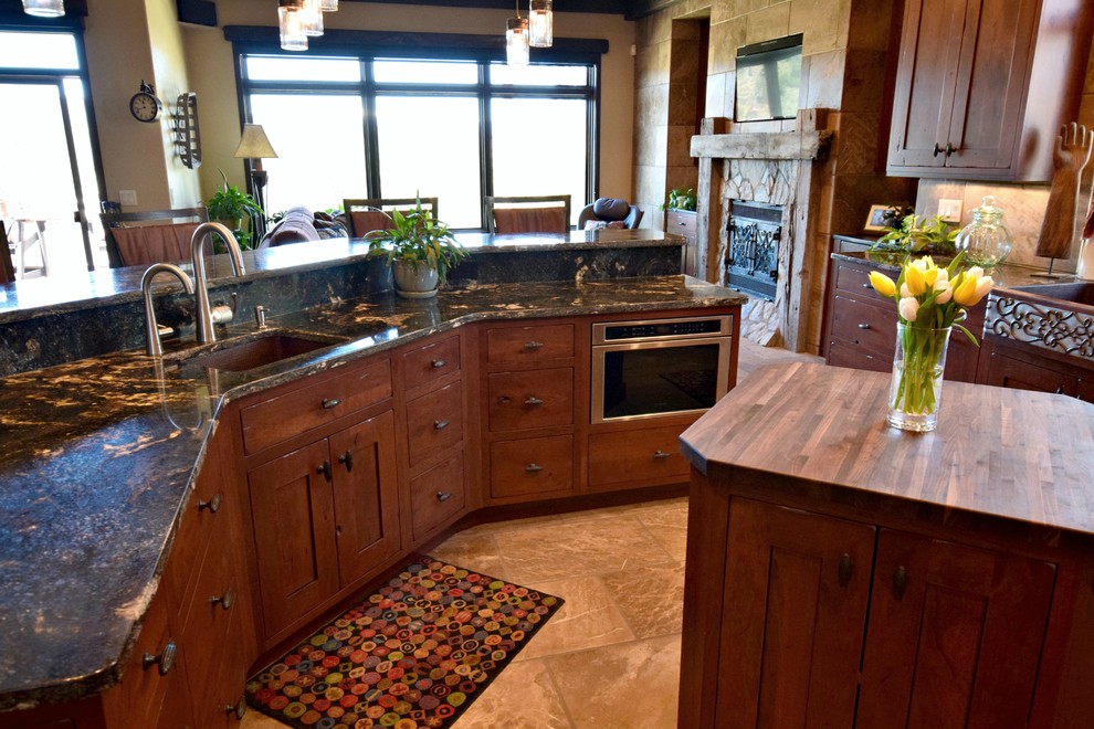 Bild på ett rustikt kök, med en rustik diskho, skåp i shakerstil, skåp i mörkt trä, granitbänkskiva, beige stänkskydd, stänkskydd i travertin, rostfria vitvaror, travertin golv, flera köksöar och beiget golv