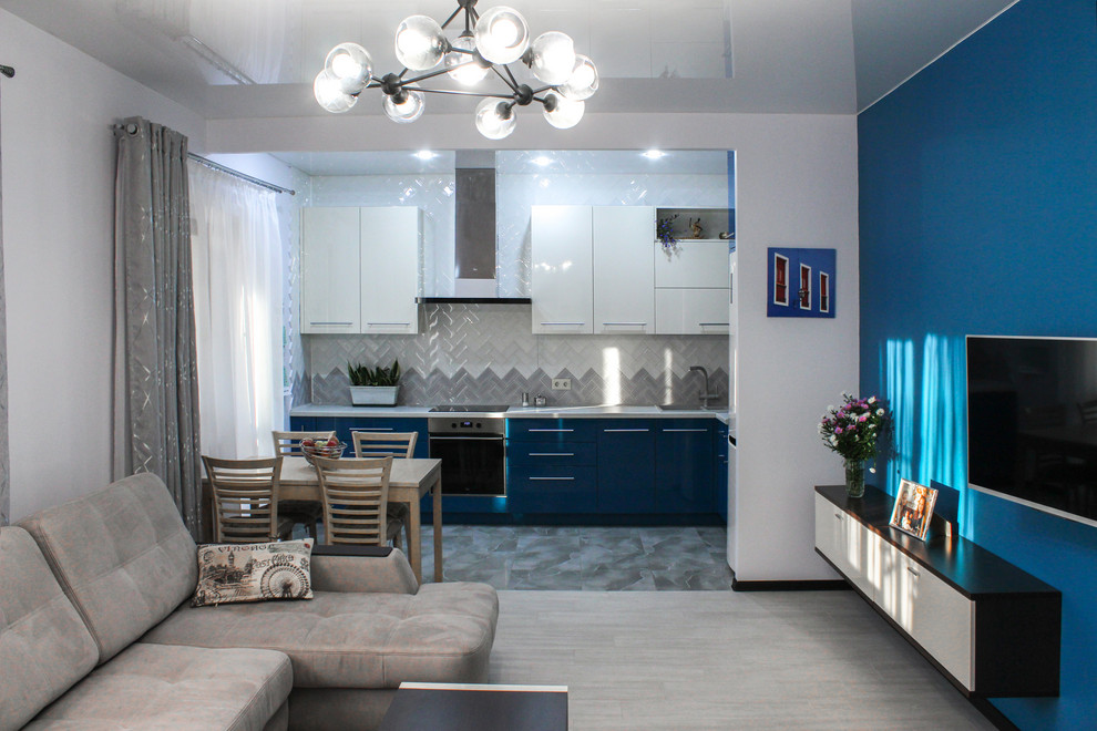 This is an example of a small contemporary l-shaped open plan kitchen in Tampa with a single-bowl sink, flat-panel cabinets, blue cabinets, engineered stone countertops, white splashback, ceramic splashback, white appliances, ceramic flooring, no island, grey floors and white worktops.
