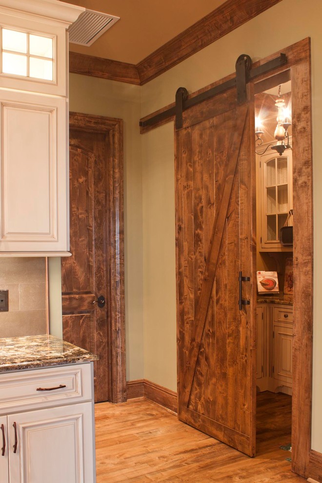 Example of a huge mountain style l-shaped medium tone wood floor and brown floor kitchen pantry design in Other with a farmhouse sink, granite countertops, an island, beaded inset cabinets, white cabinets, multicolored backsplash, mosaic tile backsplash and paneled appliances