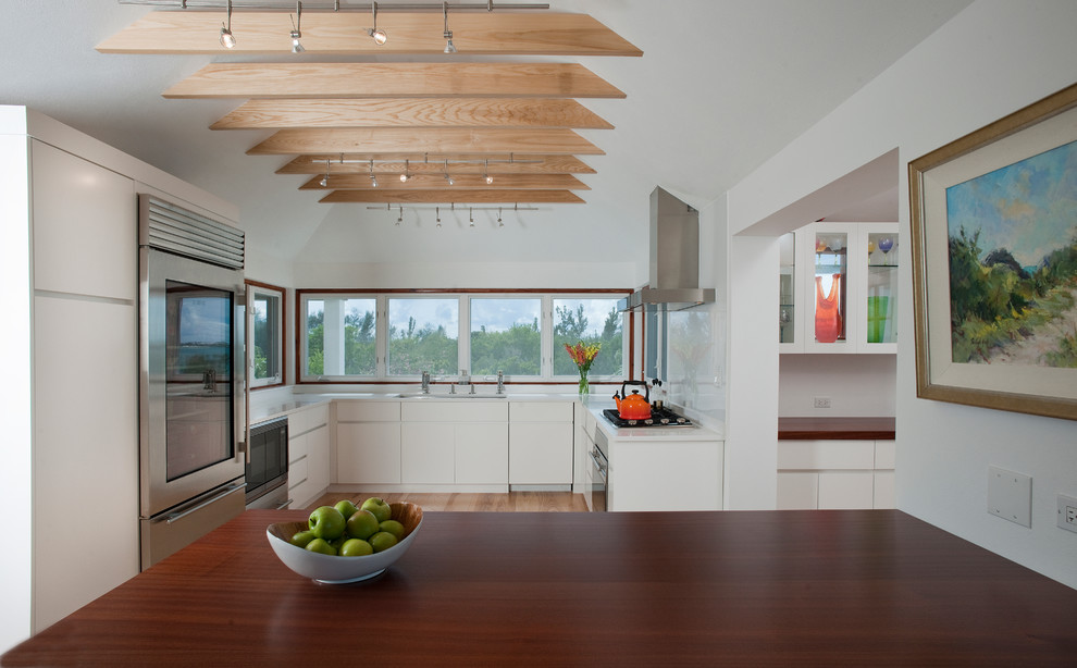 Photo of a contemporary u-shaped kitchen in Other with a submerged sink, flat-panel cabinets, white cabinets, stainless steel appliances and an island.