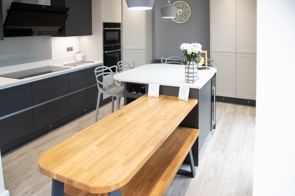 Foto di una grande cucina design con lavello da incasso, top in quarzite, paraspruzzi bianco, elettrodomestici neri, pavimento in laminato, pavimento beige e top bianco