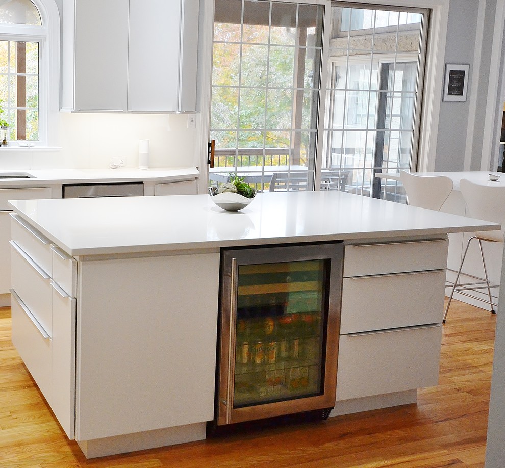 Photo of a large scandi l-shaped kitchen/diner in Philadelphia with a submerged sink, flat-panel cabinets, white cabinets, engineered stone countertops, white splashback, ceramic splashback, stainless steel appliances, medium hardwood flooring, an island and brown floors.
