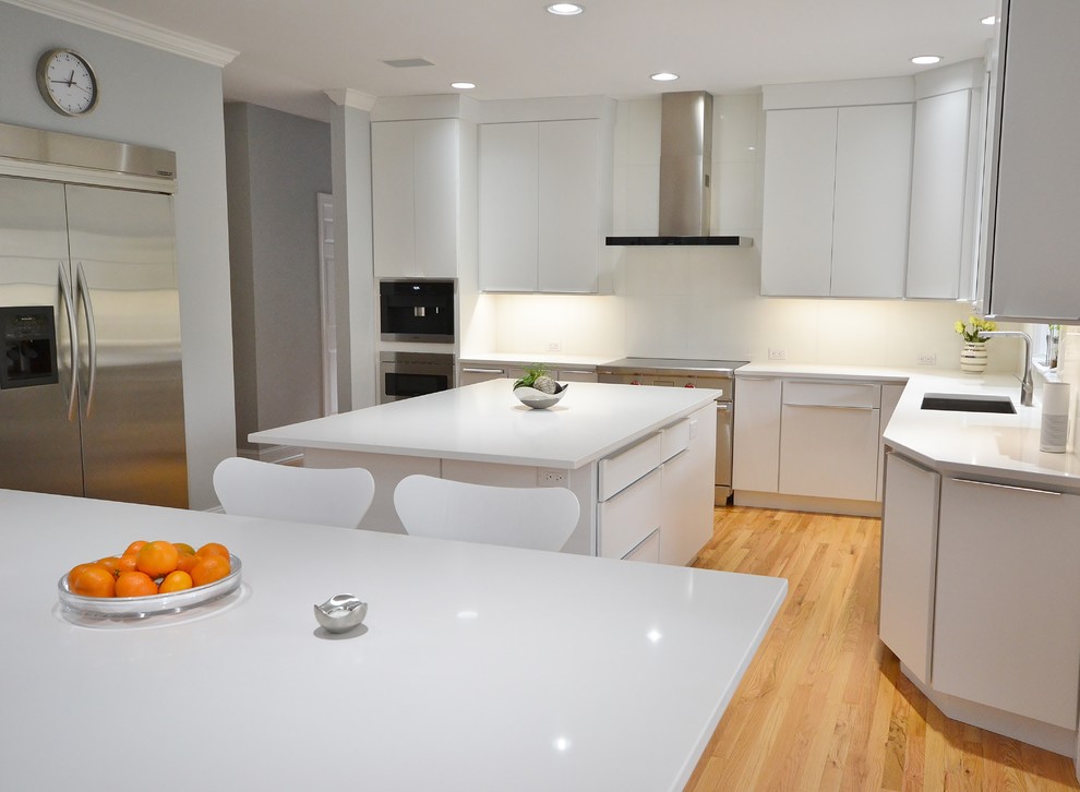 Example of a large danish l-shaped medium tone wood floor and brown floor eat-in kitchen design in Philadelphia with an undermount sink, flat-panel cabinets, white cabinets, quartz countertops, white backsplash, ceramic backsplash, stainless steel appliances and an island