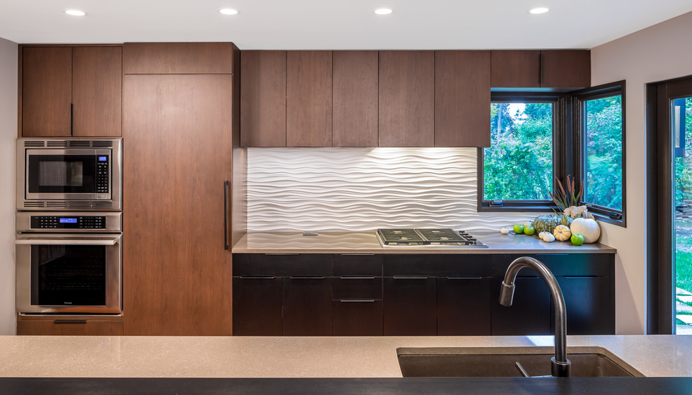 Idée de décoration pour une grande cuisine américaine linéaire minimaliste en bois brun avec un évier 2 bacs, un placard à porte plane, une crédence blanche, un électroménager en acier inoxydable et une péninsule.