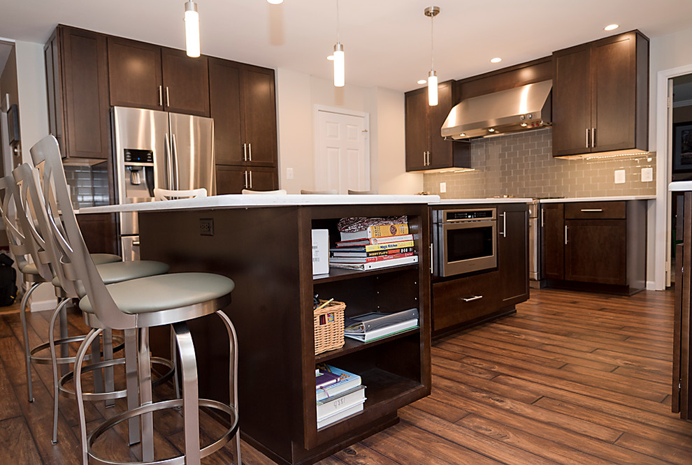 Example of a large minimalist l-shaped vinyl floor kitchen pantry design in DC Metro with an undermount sink, shaker cabinets, dark wood cabinets, quartz countertops, beige backsplash, subway tile backsplash, stainless steel appliances and an island