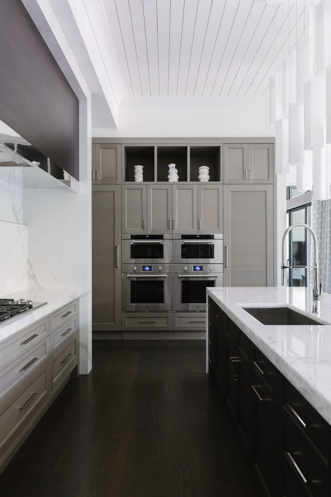 Example of a mid-sized trendy galley dark wood floor and brown floor enclosed kitchen design in Chicago with an undermount sink, beaded inset cabinets, medium tone wood cabinets, tile countertops, white backsplash, porcelain backsplash, stainless steel appliances, an island and white countertops