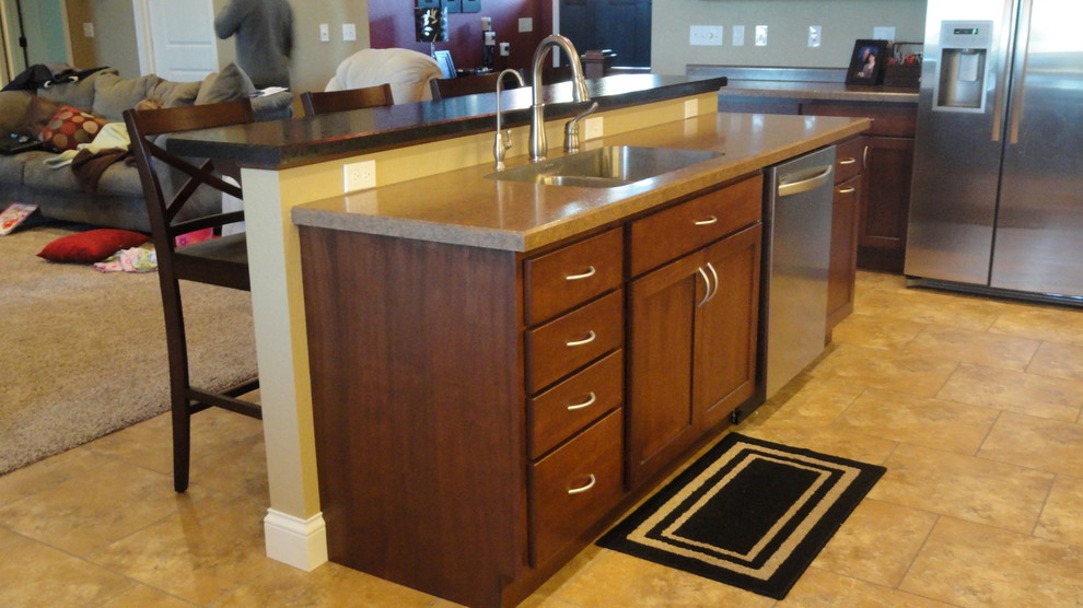 Immagine di una cucina di medie dimensioni con lavello sottopiano, ante lisce, ante in legno bruno, top in laminato e elettrodomestici in acciaio inossidabile