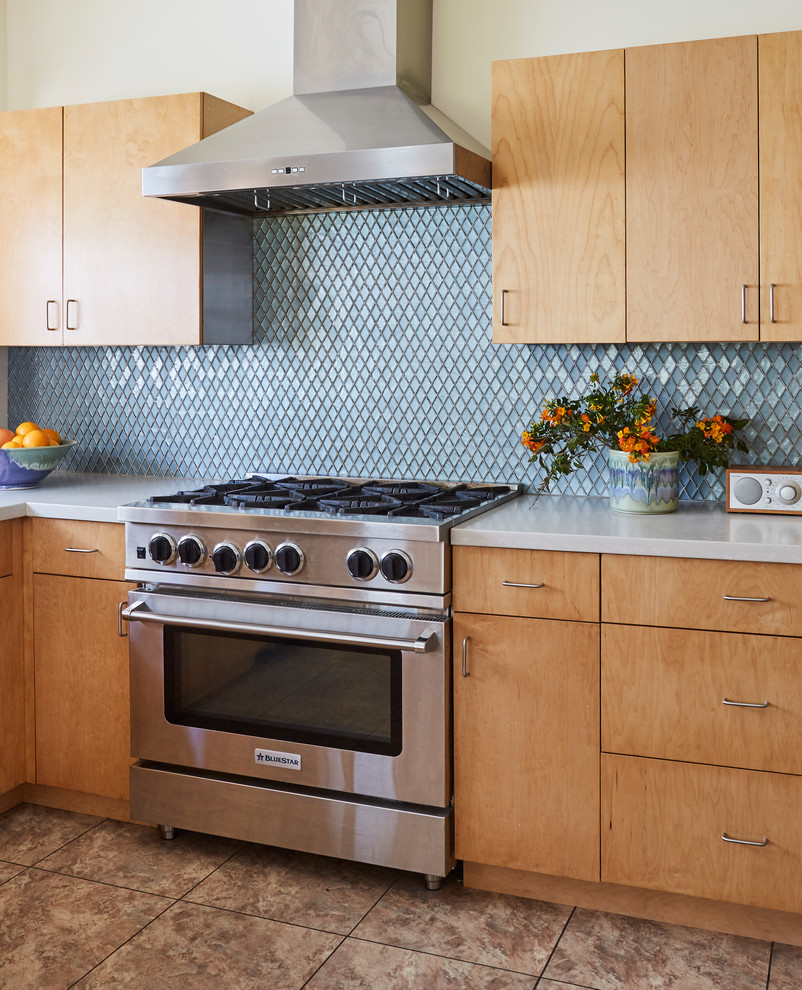 Foto på ett avskilt, mellanstort funkis vit u-kök, med en undermonterad diskho, släta luckor, skåp i ljust trä, bänkskiva i kvarts, blått stänkskydd, stänkskydd i glaskakel, rostfria vitvaror, vinylgolv och flerfärgat golv