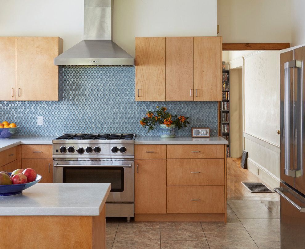 Inredning av ett modernt avskilt, mellanstort vit vitt u-kök, med en undermonterad diskho, släta luckor, skåp i ljust trä, bänkskiva i kvarts, blått stänkskydd, stänkskydd i glaskakel, rostfria vitvaror, vinylgolv och flerfärgat golv