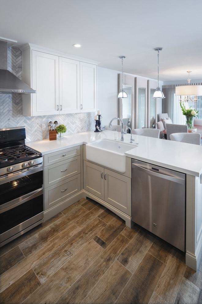 Inspiration for a mid-sized coastal l-shaped porcelain tile eat-in kitchen remodel in San Diego with a farmhouse sink, shaker cabinets, white cabinets, solid surface countertops, multicolored backsplash, mosaic tile backsplash, stainless steel appliances and a peninsula