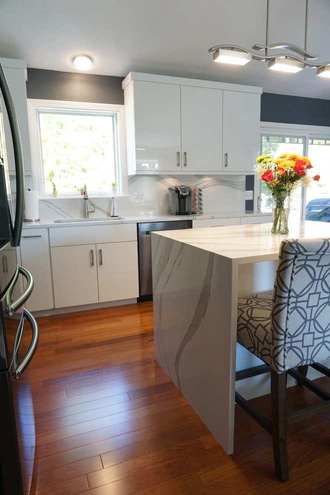 Example of a mid-sized trendy l-shaped dark wood floor and red floor eat-in kitchen design in Providence with an undermount sink, flat-panel cabinets, white cabinets, quartz countertops, white backsplash, stone slab backsplash, stainless steel appliances, an island and white countertops