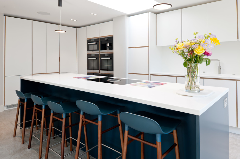 This is an example of a medium sized contemporary l-shaped kitchen in Kent with a submerged sink, flat-panel cabinets, quartz worktops, an island, grey floors and white worktops.