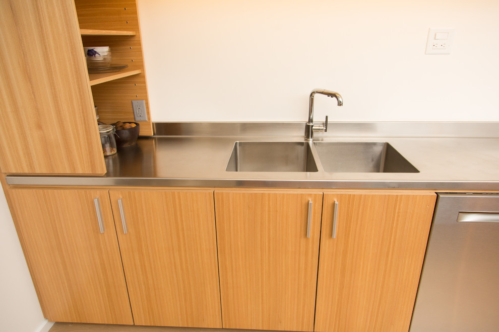 Immagine di una cucina minimal di medie dimensioni con lavello integrato, ante lisce, ante in legno scuro, top in acciaio inossidabile, elettrodomestici in acciaio inossidabile e pavimento beige