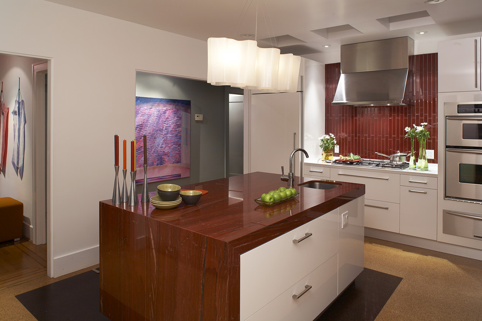 Inspiration for a mid-sized modern u-shaped cork floor and orange floor eat-in kitchen remodel in San Francisco with a drop-in sink, flat-panel cabinets, white cabinets, granite countertops, red backsplash, ceramic backsplash, stainless steel appliances and an island