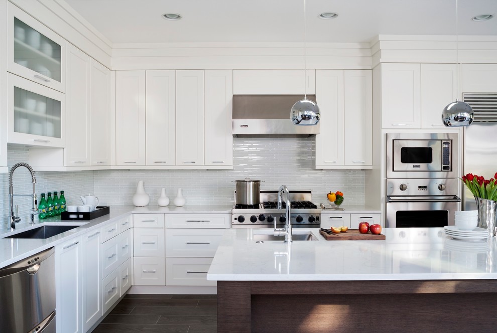 Medium sized classic l-shaped enclosed kitchen in DC Metro with a submerged sink, shaker cabinets, white cabinets, engineered stone countertops, white splashback, glass tiled splashback, stainless steel appliances, ceramic flooring, an island and brown floors.