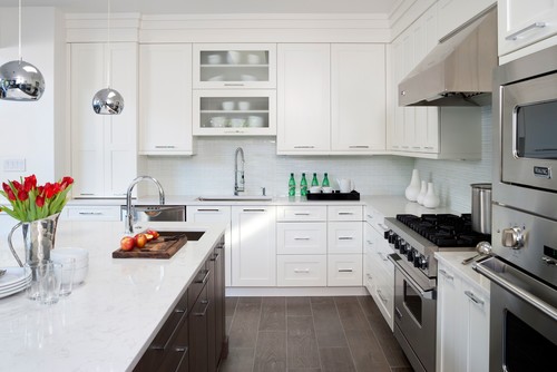 Kitchen & Bathroom Cabinets – bright white shaker kitchen with glass-front uppers, quartz island with dark wood base, stainless appliances and chrome pendants.