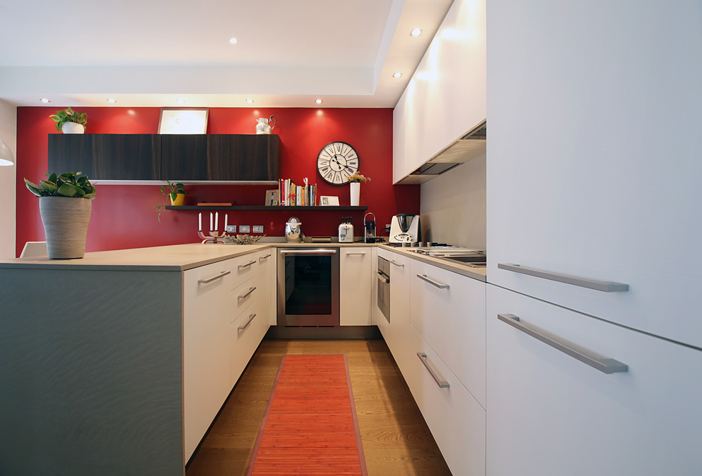 Mittelgroße Moderne Wohnküche in U-Form mit integriertem Waschbecken, Schrankfronten mit vertiefter Füllung, weißen Schränken, Quarzit-Arbeitsplatte, Küchenrückwand in Rot, Küchengeräten aus Edelstahl, braunem Holzboden und Halbinsel in Mailand