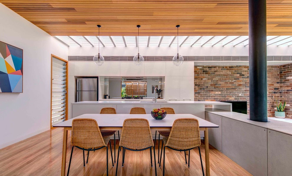 Immagine di una cucina minimalista con lavello a doppia vasca, pavimento in legno massello medio, paraspruzzi a specchio e elettrodomestici in acciaio inossidabile