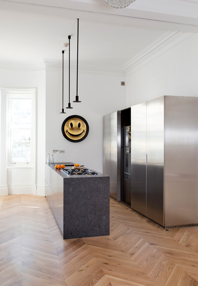 Immagine di una cucina contemporanea di medie dimensioni con ante lisce, ante in acciaio inossidabile, pavimento in legno massello medio, top in granito, elettrodomestici in acciaio inossidabile, pavimento beige e top nero