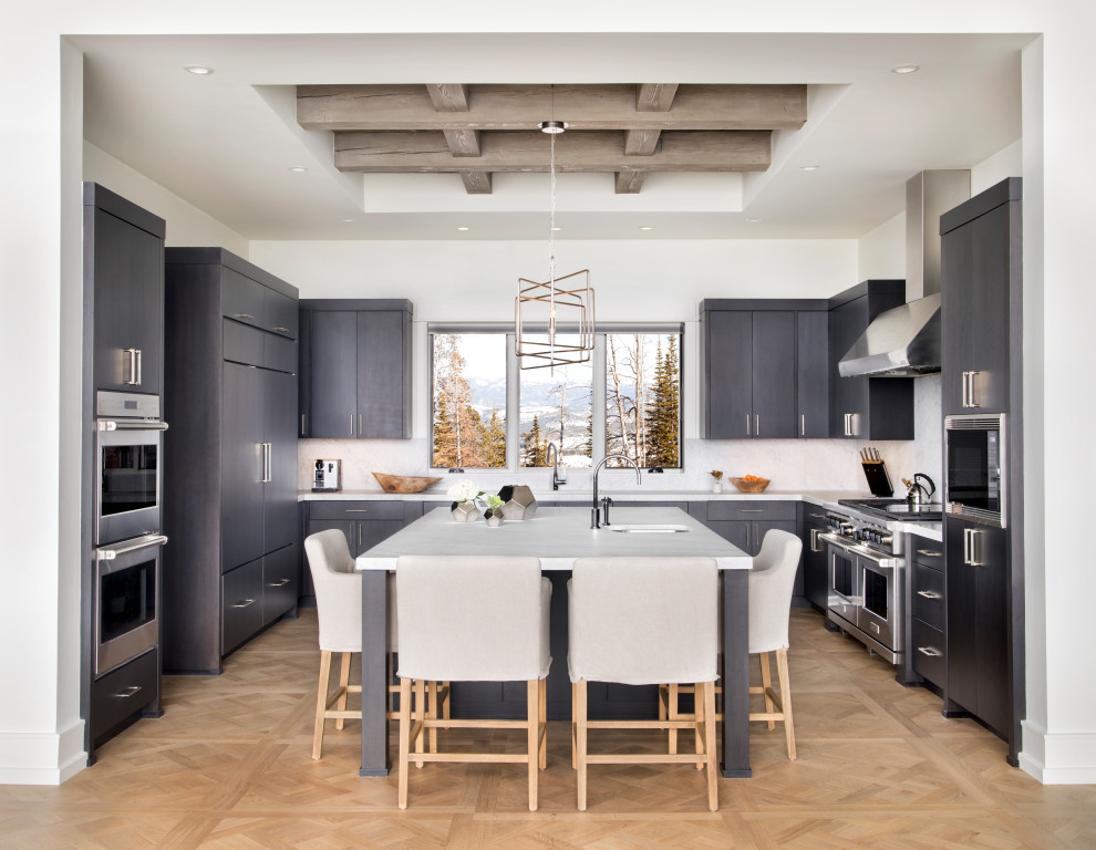 Rustic u-shaped kitchen in Other with a submerged sink, flat-panel cabinets, grey cabinets, white splashback, stainless steel appliances, medium hardwood flooring, an island, brown floors, exposed beams and a drop ceiling.