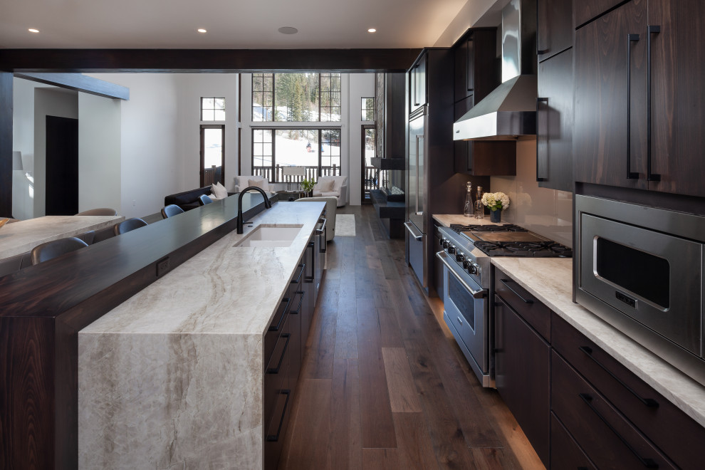 Mid-sized minimalist medium tone wood floor and brown floor open concept kitchen photo in Other with an undermount sink, flat-panel cabinets, dark wood cabinets, quartzite countertops, gray backsplash, glass sheet backsplash, stainless steel appliances, an island and beige countertops