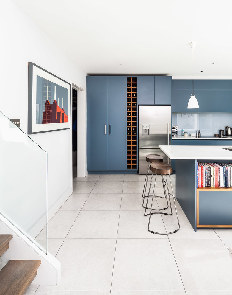 This is an example of a contemporary kitchen/diner in London with flat-panel cabinets, composite countertops, grey splashback, glass sheet splashback, stainless steel appliances, porcelain flooring and an island.