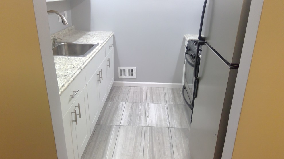 This is an example of a small contemporary u-shaped kitchen/diner in Newark with a single-bowl sink, shaker cabinets, white cabinets, laminate countertops, stainless steel appliances, cement flooring, grey floors and grey worktops.
