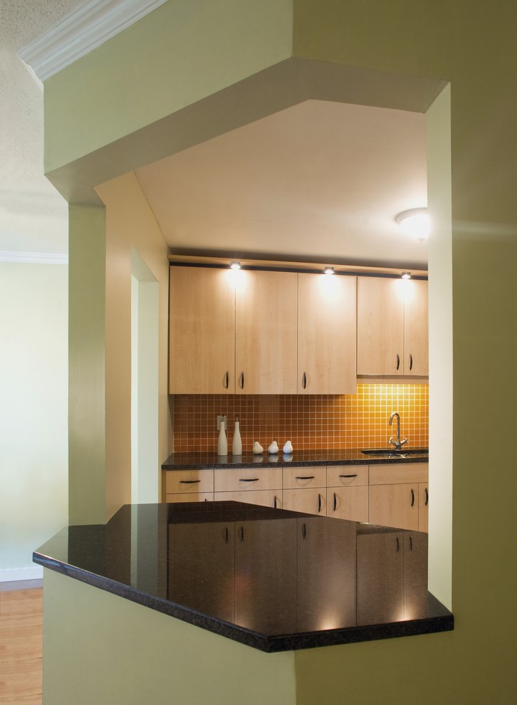На фото: кухня в стиле фьюжн с плоскими фасадами, светлыми деревянными фасадами и оранжевым фартуком