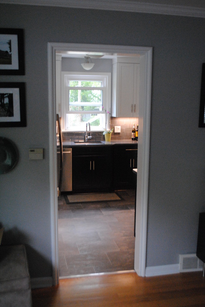 Modern inredning av ett avskilt, litet u-kök, med en undermonterad diskho, skåp i shakerstil, svarta skåp, bänkskiva i kvarts, grått stänkskydd, stänkskydd i glaskakel, rostfria vitvaror och vinylgolv