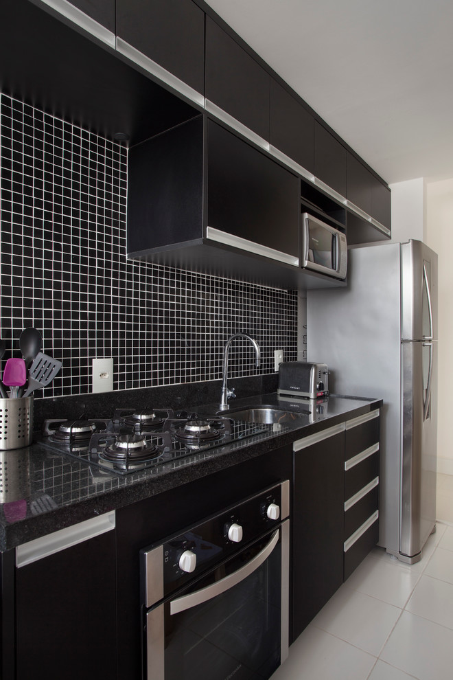 Kleine Moderne Küche mit schwarzen Schränken, Küchenrückwand in Schwarz, Küchengeräten aus Edelstahl und Keramikboden in Sonstige