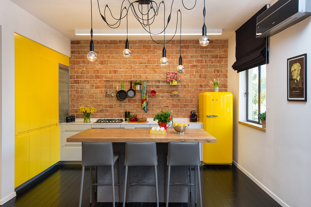 Свежая идея для дизайна: маленькая угловая, отдельная кухня в стиле фьюжн с островом, плоскими фасадами, желтыми фасадами, цветной техникой и деревянным полом для на участке и в саду - отличное фото интерьера