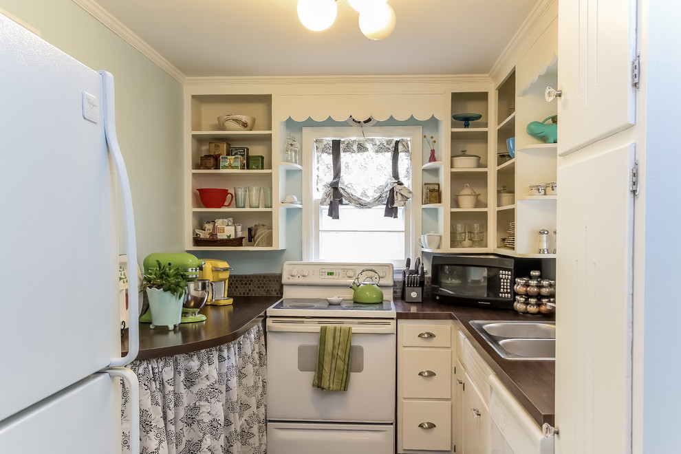 This is an example of a small eclectic u-shaped enclosed kitchen in Grand Rapids with a built-in sink, flat-panel cabinets, white cabinets, laminate countertops, brown splashback, ceramic splashback, white appliances, dark hardwood flooring and no island.