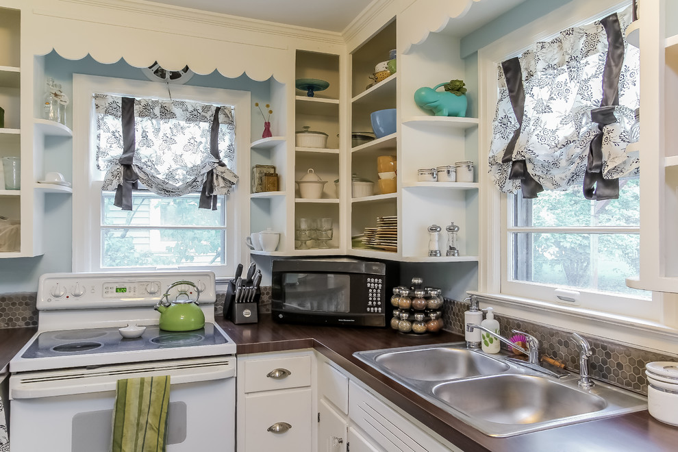 This is an example of a small bohemian u-shaped enclosed kitchen in Grand Rapids with a built-in sink, flat-panel cabinets, white cabinets, brown splashback, ceramic splashback, white appliances, dark hardwood flooring and no island.