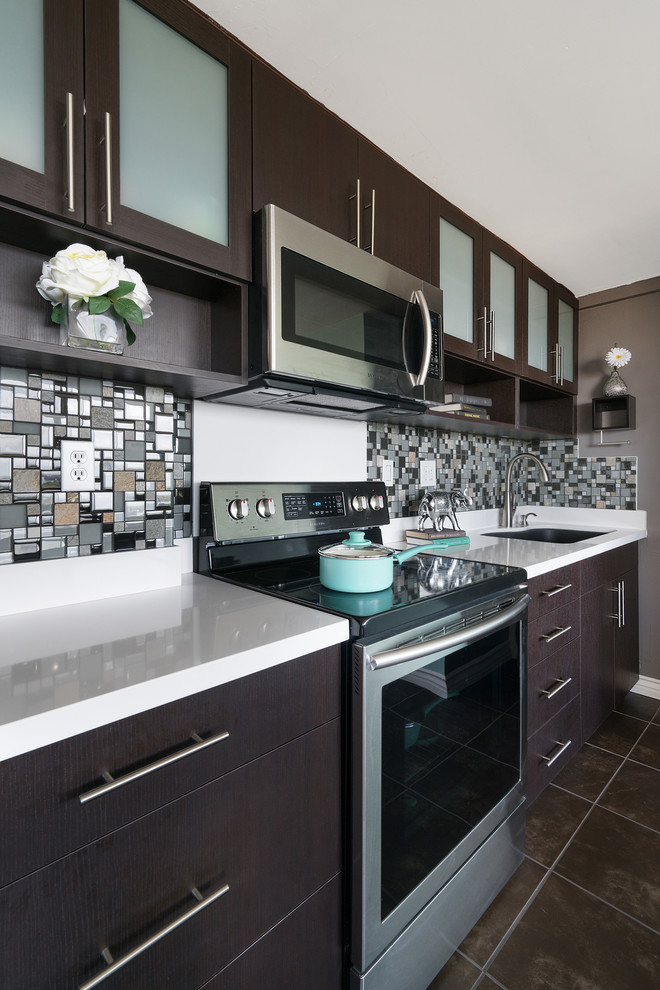 Small trendy single-wall ceramic tile open concept kitchen photo in Hawaii with an undermount sink, flat-panel cabinets, dark wood cabinets, solid surface countertops, multicolored backsplash, mosaic tile backsplash, stainless steel appliances and an island