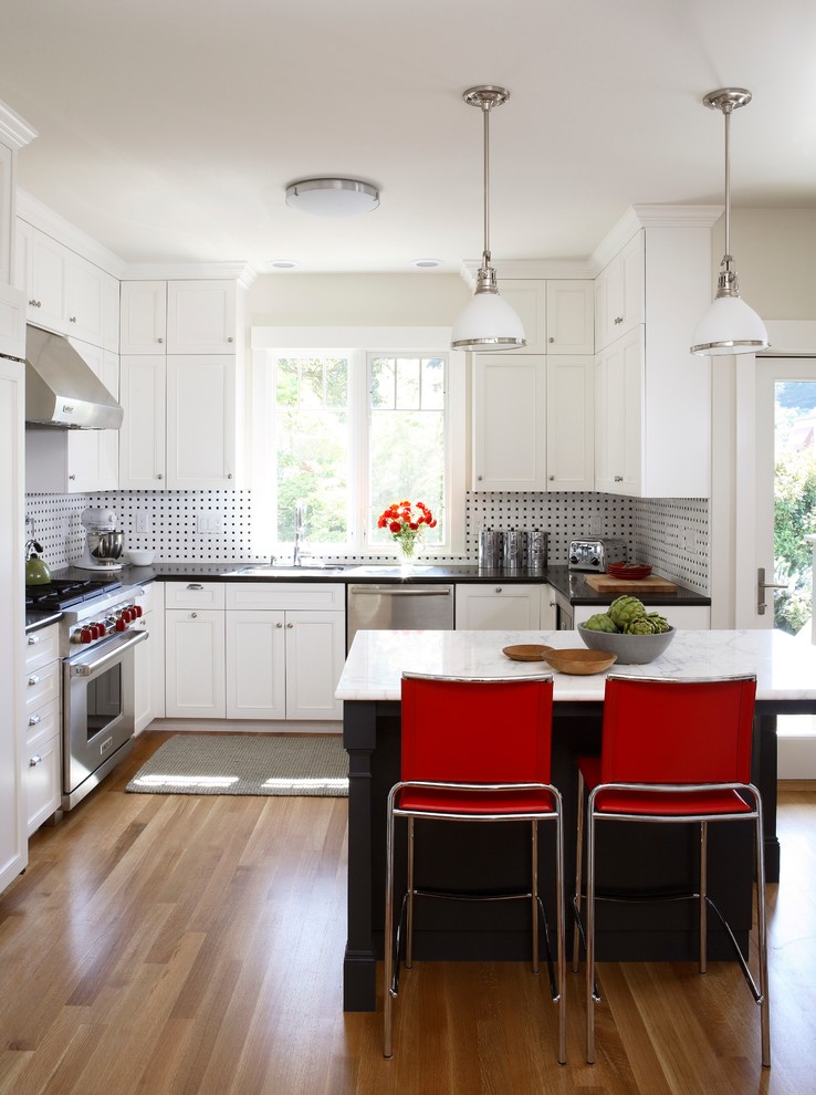 Photo of a traditional u-shaped kitchen in San Francisco with a submerged sink, shaker cabinets, white cabinets, multi-coloured splashback, mosaic tiled splashback, stainless steel appliances, medium hardwood flooring and an island.
