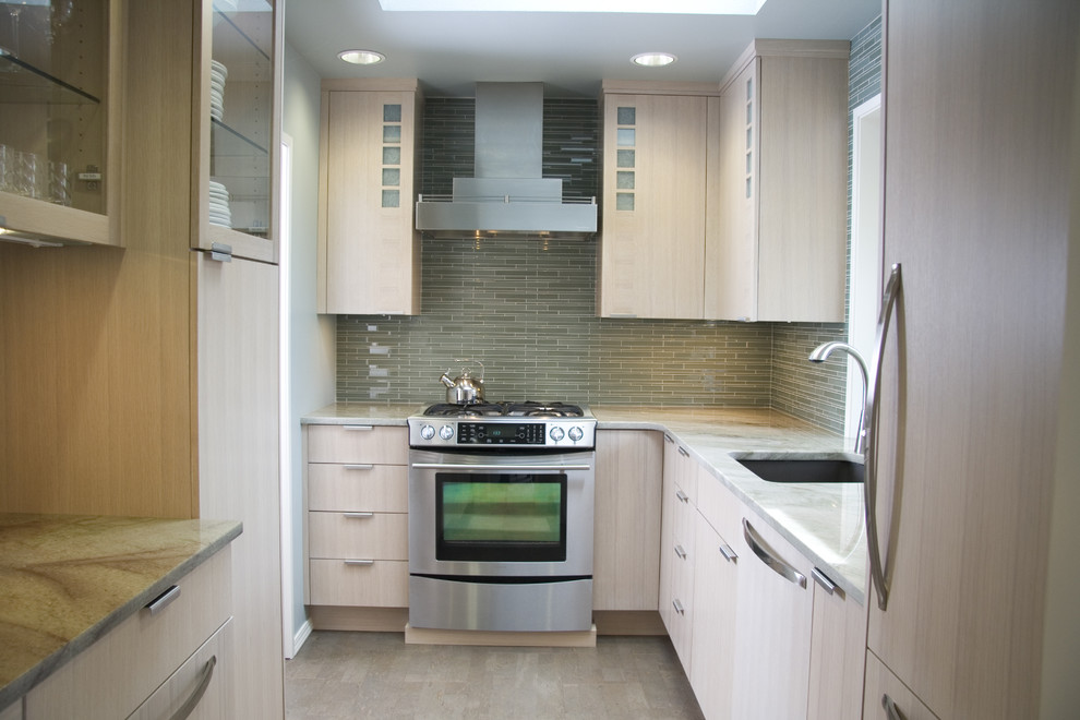 Modern inredning av ett avskilt u-kök, med släta luckor, rostfria vitvaror, granitbänkskiva, en undermonterad diskho, skåp i ljust trä, grönt stänkskydd och stänkskydd i glaskakel