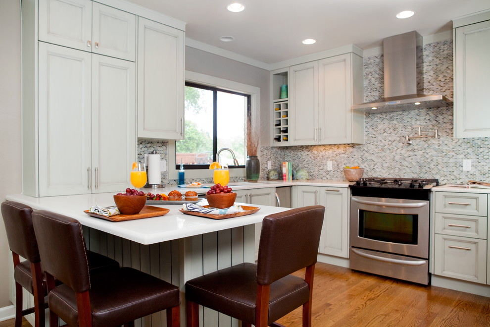 Cette photo montre une cuisine chic avec un placard avec porte à panneau encastré, une crédence multicolore, une crédence en mosaïque et un électroménager en acier inoxydable.