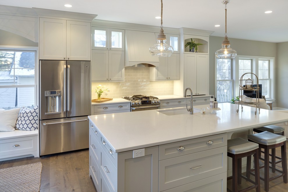 Kitchen - small transitional single-wall medium tone wood floor kitchen idea in Minneapolis with an undermount sink, shaker cabinets, white cabinets, quartz countertops, gray backsplash, subway tile backsplash, stainless steel appliances and an island