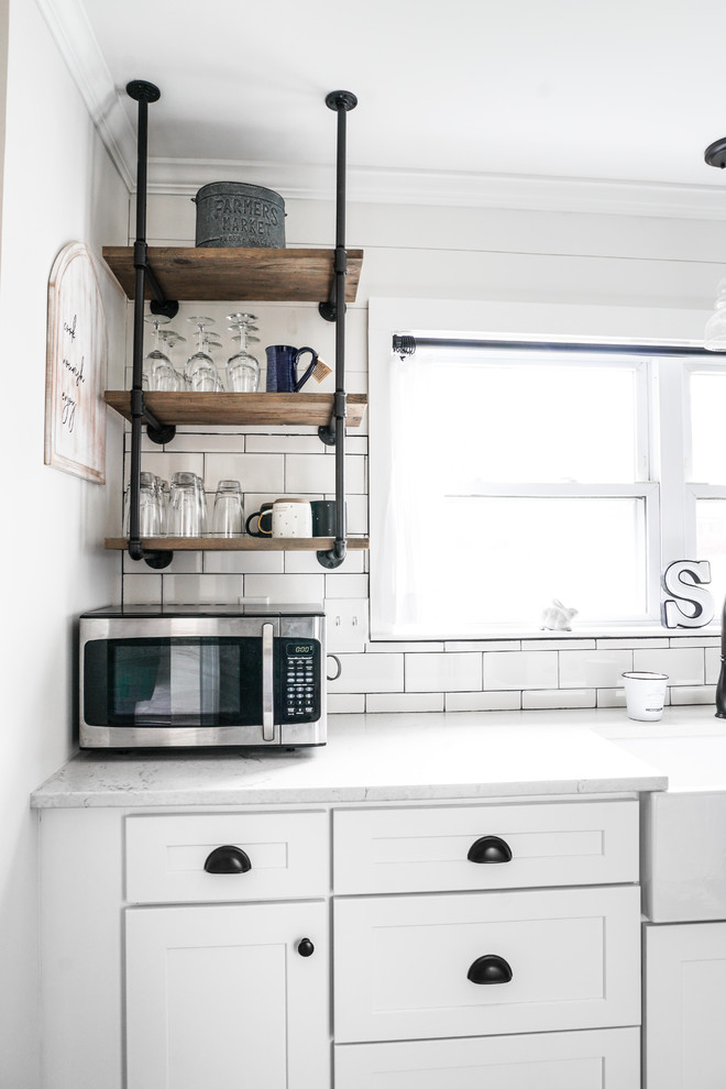 Modelo de cocina comedor campestre pequeña sin isla con armarios estilo shaker, puertas de armario blancas, encimera de cuarzo compacto, salpicadero blanco, salpicadero de azulejos de cerámica y encimeras blancas