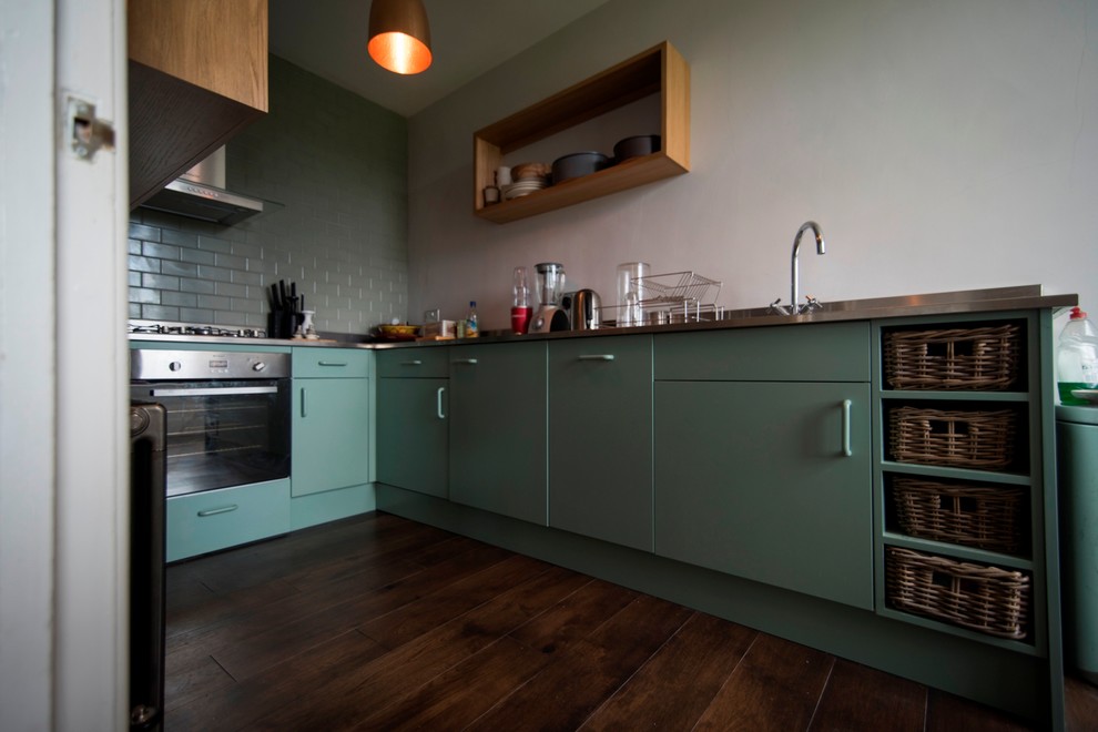 Ispirazione per una piccola cucina parallela minimal chiusa con lavello da incasso, ante lisce, ante verdi, top in acciaio inossidabile e pavimento in legno massello medio