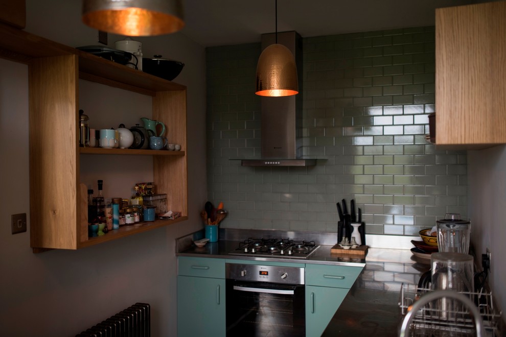ウィルトシャーにあるお手頃価格の小さなコンテンポラリースタイルのおしゃれなキッチン (ドロップインシンク、フラットパネル扉のキャビネット、緑のキャビネット、ステンレスカウンター、無垢フローリング) の写真