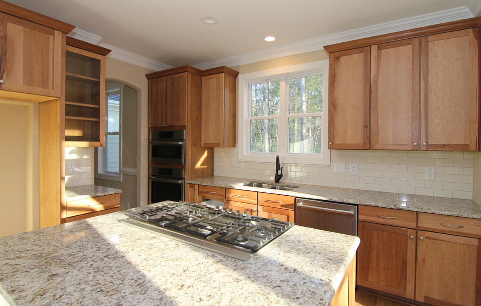 Exempel på ett mellanstort klassiskt kök, med en dubbel diskho, skåp i shakerstil, skåp i mellenmörkt trä, granitbänkskiva, vitt stänkskydd, stänkskydd i keramik, rostfria vitvaror, mellanmörkt trägolv och en köksö