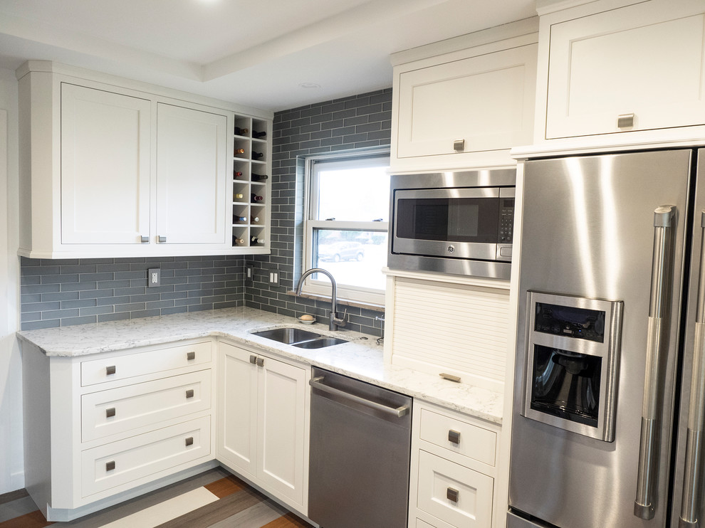 Photo of a small modern u-shaped enclosed kitchen in Detroit with a submerged sink, flat-panel cabinets, white cabinets, quartz worktops, grey splashback, glass tiled splashback, stainless steel appliances, vinyl flooring and multi-coloured floors.