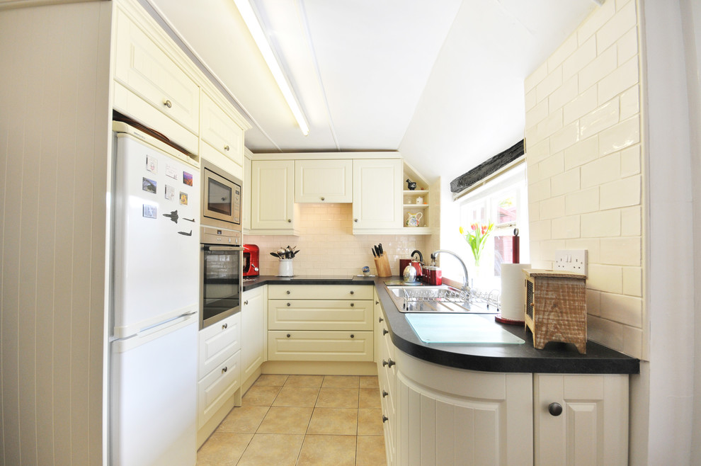 Inspiration for a country kitchen in Kent with a built-in sink, beige splashback, metro tiled splashback, stainless steel appliances and ceramic flooring.
