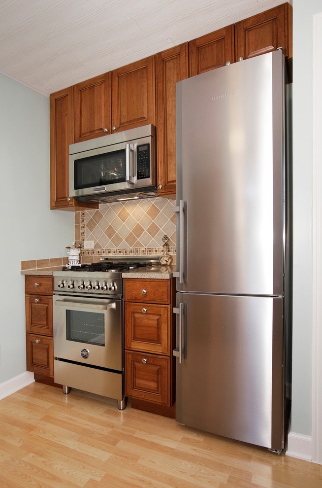 Cette photo montre une petite cuisine parallèle chic avec un électroménager en acier inoxydable et parquet clair.