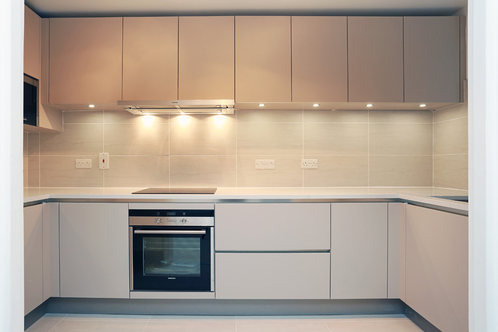 Idée de décoration pour une petite cuisine minimaliste en U fermée avec des portes de placard beiges.