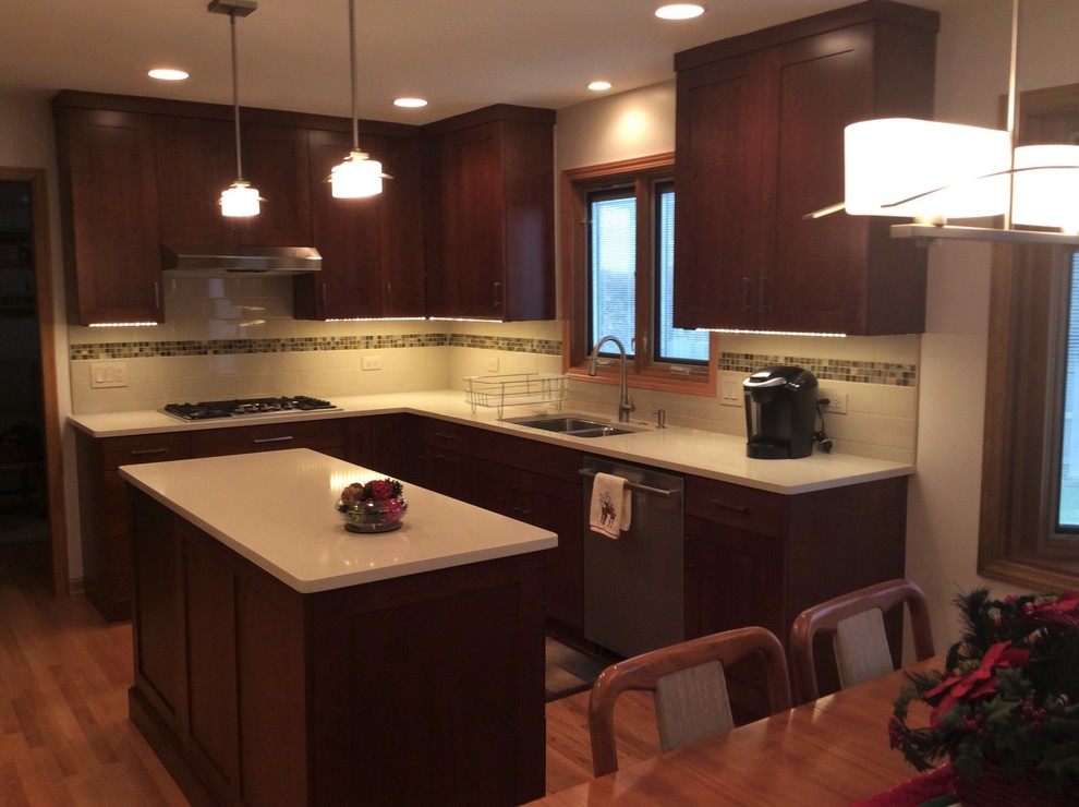 Mid-sized elegant l-shaped light wood floor eat-in kitchen photo in Chicago with a double-bowl sink, shaker cabinets, quartz countertops, subway tile backsplash, stainless steel appliances, an island and red cabinets